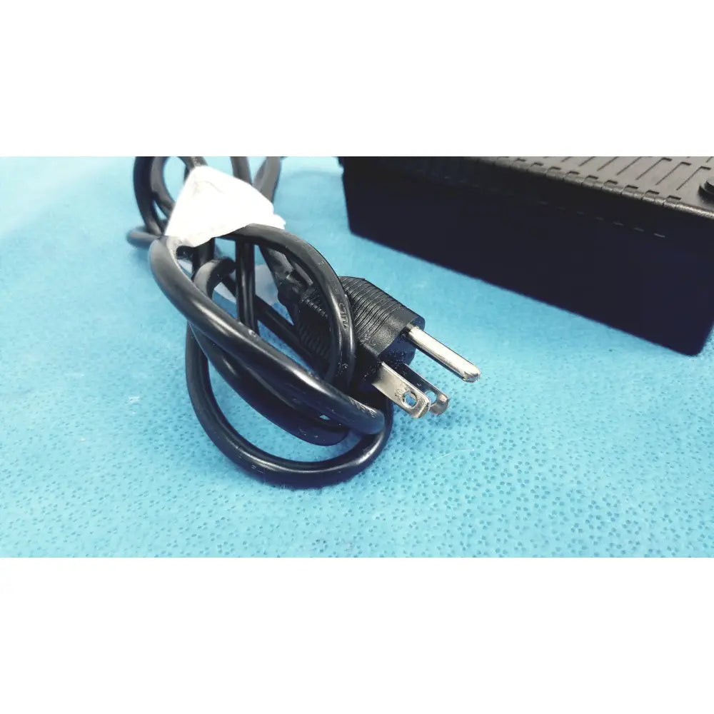 Black coiled power cord with three-prong plug and white label for Protek Power model PMP60-12-B16 AC adaptor