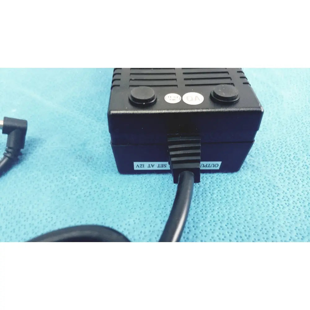 Black plastic protek power model pmp60-12-b16 ac adaptor with two circular buttons and coiled cable