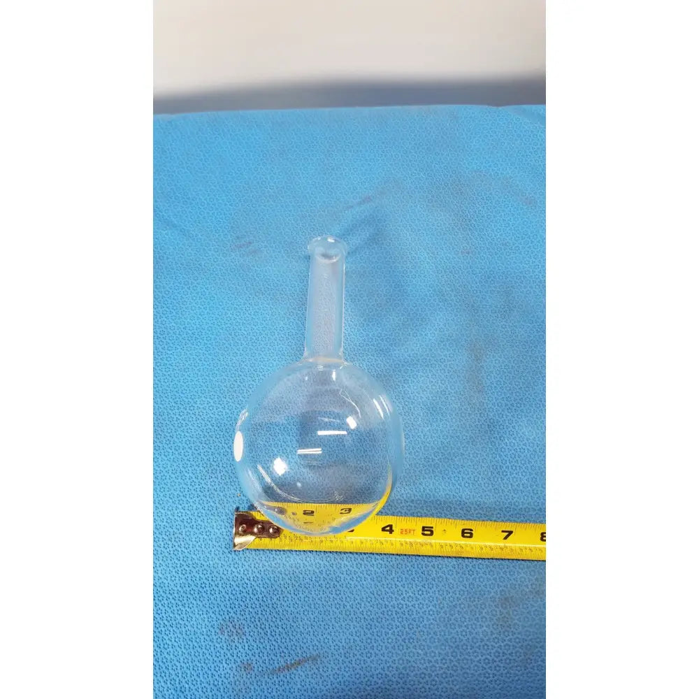 Pyrex 500ml single neck round bottom boiling flask made of clear glass resting on blue surface with yellow tape