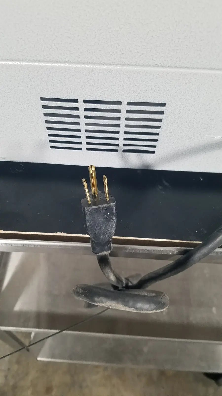 Black electrical plug with three gold prongs connected to a cord at the back of quincy lab 30gc gravity convection oven