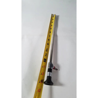 A metallic r wolf 8934.441 panoview 10mm 0 degree rigid lumina endoscope with black rubber grip and silver joints next to tape measure