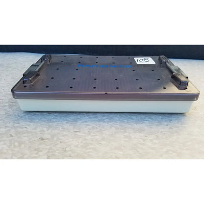 Radionics surgical sterlization case tray in dark gray plastic with white base and multiple holes on the lid features rainbow branding