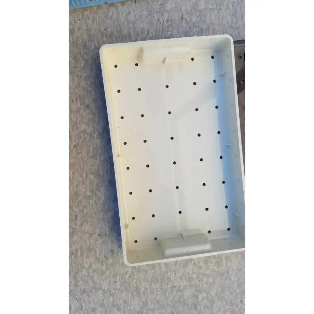 White plastic radionics surgical sterlization case tray with evenly spaced circular holes for instrument organization