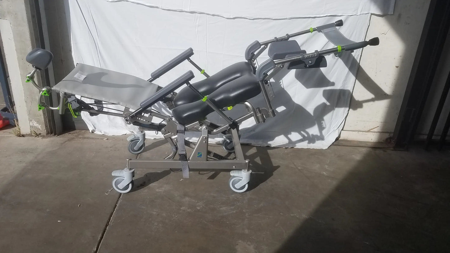 Raz attendant tilt shower commode chair with black padded sections, silver frame, green accents, and caster wheels for mobility