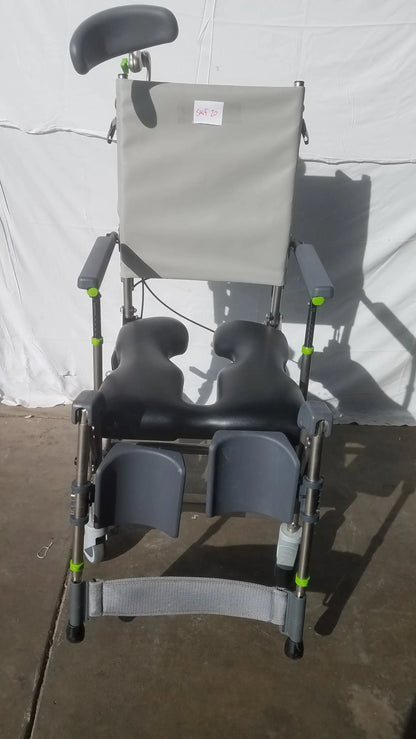 Gray Raz Attendant tilt shower commode chair with adjustable recliner, black padding, green metal frame accents