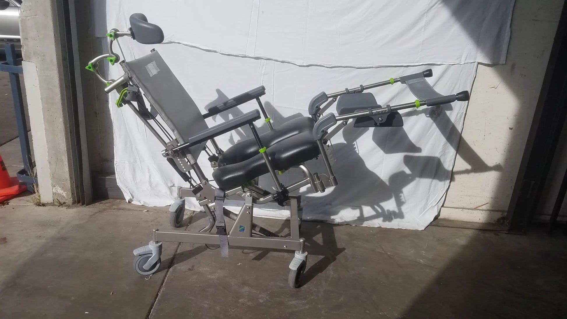 Gray and black adjustable raz attendant tilt shower commode chair with green accent hardware for medical use