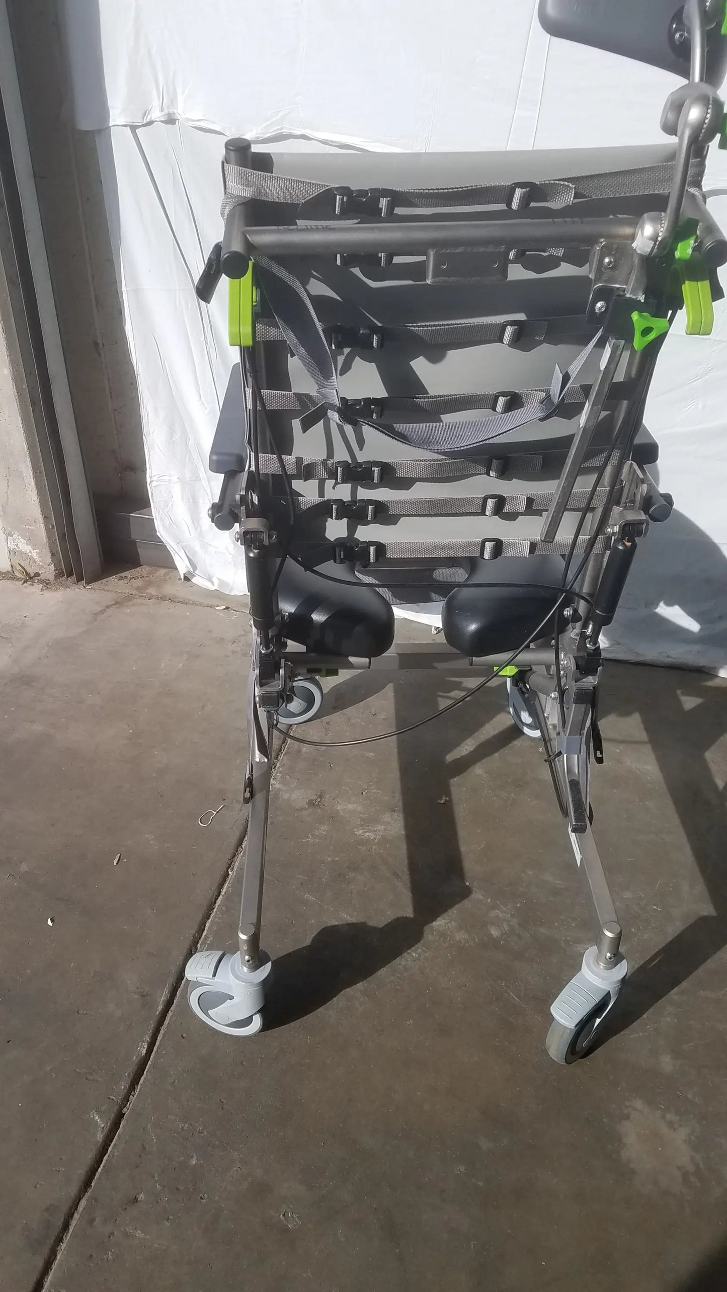 Gray and black raz attendant tilt shower commode chair with adjustable straps green clips and four wheels for support
