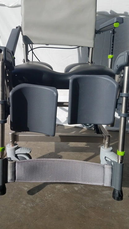 Gray plastic and metal adjustable raz attendant tilt shower commode chair with green accent caps on legs