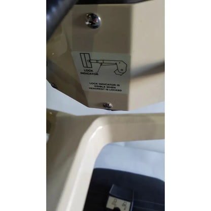 Beige plastic headrest lock indicator with diagram on the reliance medical products model 6100 exam chair with footswitch and headlight
