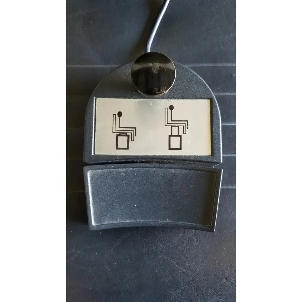 Black plastic seat adjustment pedal with silver button and chair position icons on reliance medical products model 6100 exam chair