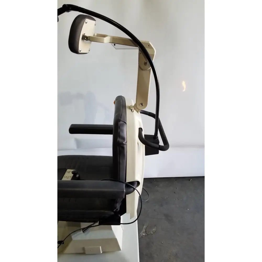 Beige and black reliance medical products model 6100 exam chair with padded armrests and adjustable neck retraction mechanism