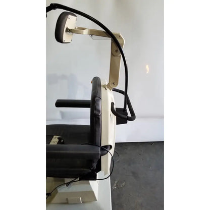 Beige and black reliance medical products model 6100 exam chair with padded armrests and adjustable neck retraction mechanism