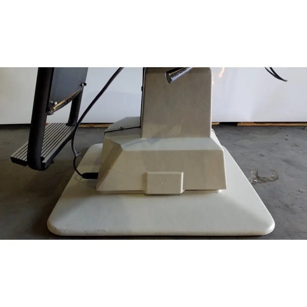 Beige plastic base of reliance medical products model 6100 exam chair with rectangular foot pedal and integrated power cord