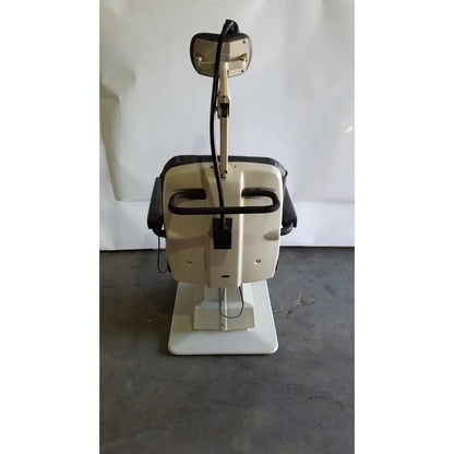 Beige and black dental exam chair with adjustable headrest and armrests by reliance medical products model 6100