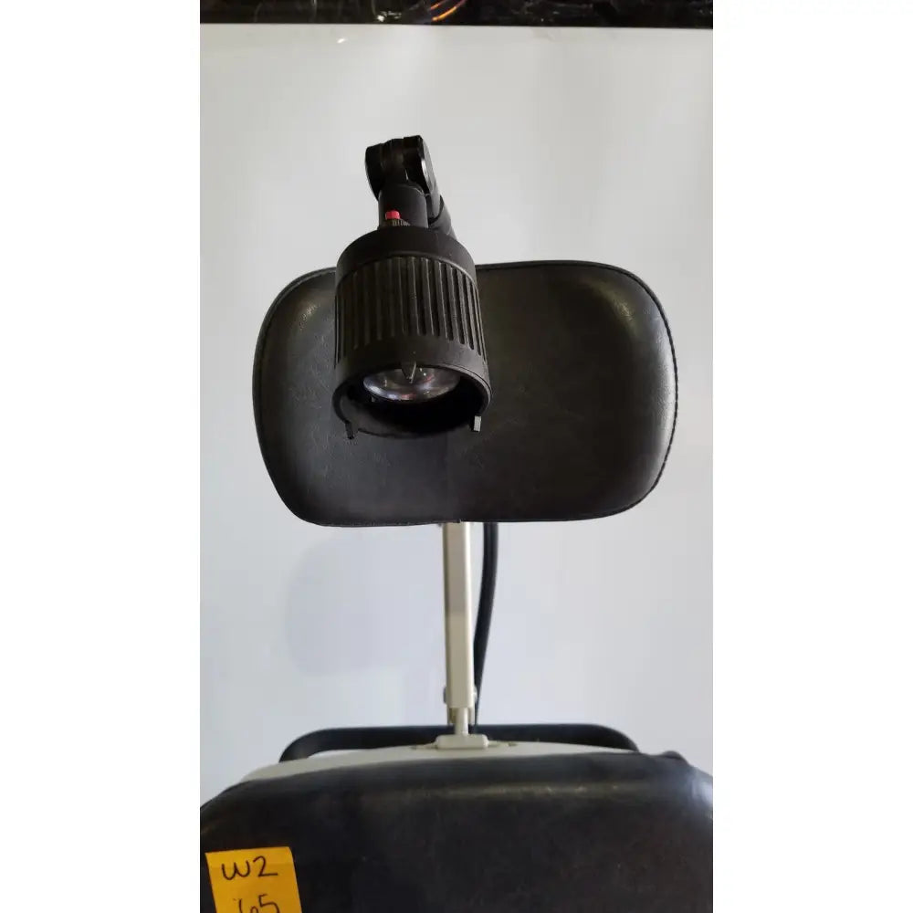 Black adjustable headrest-mounted lamp with ribbed housing and articulated arm on reliance medical products model 6100 exam chair