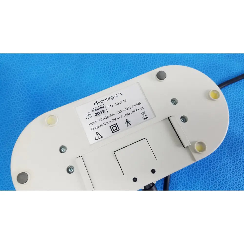 White oval-shaped ri-charger l charging base with four yellow indicator lights and reuse medical technical label