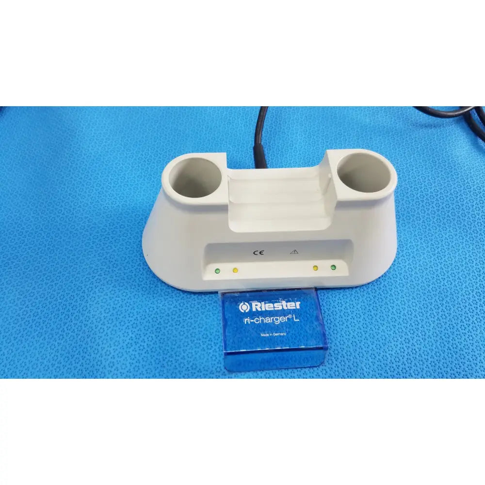 White plastic riester ri-charger l charging base with two circular slots and indicator lights for reuse medical devices