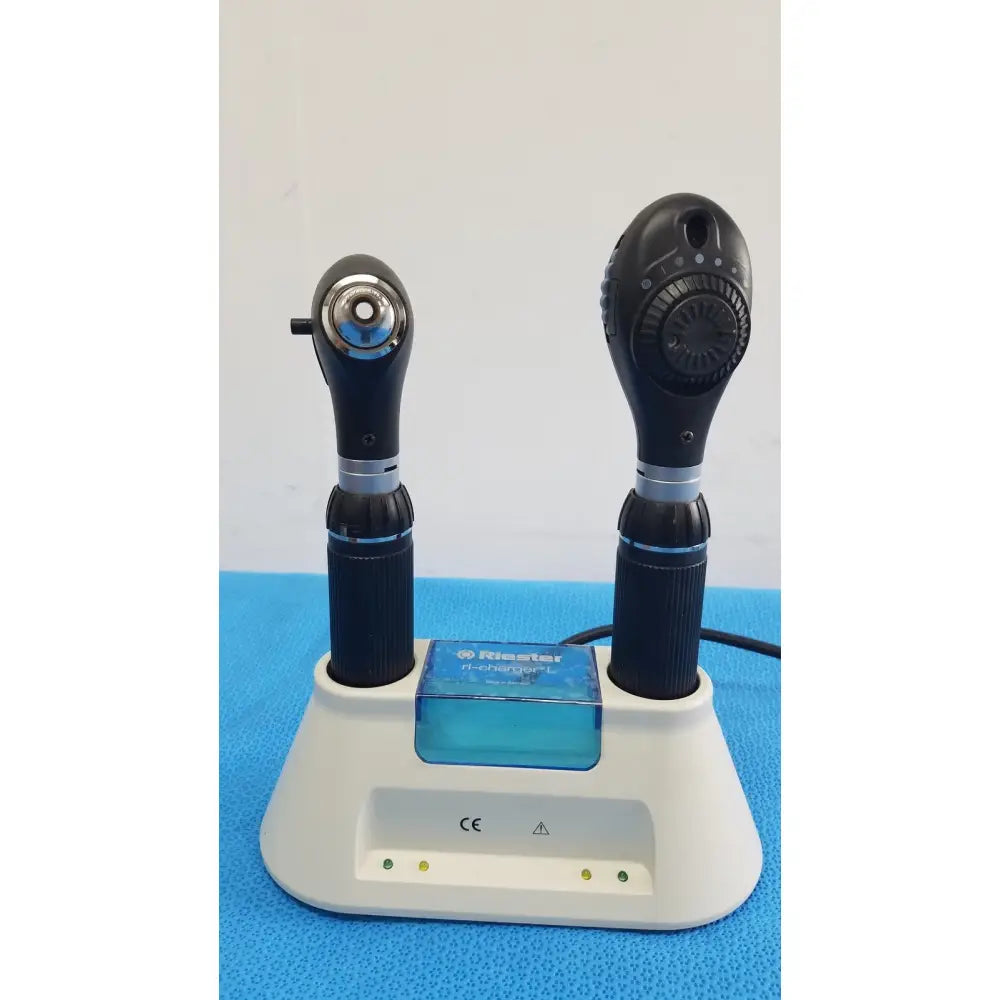 Two black rieker h-checker l otoscopes with textured grips and silver accents sit in a white ri-charger l charging base