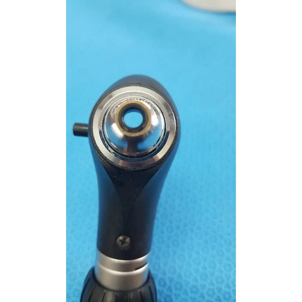 Black and silver dental handpiece with polished metallic tip and textured grip on riester ri-charger l charging base