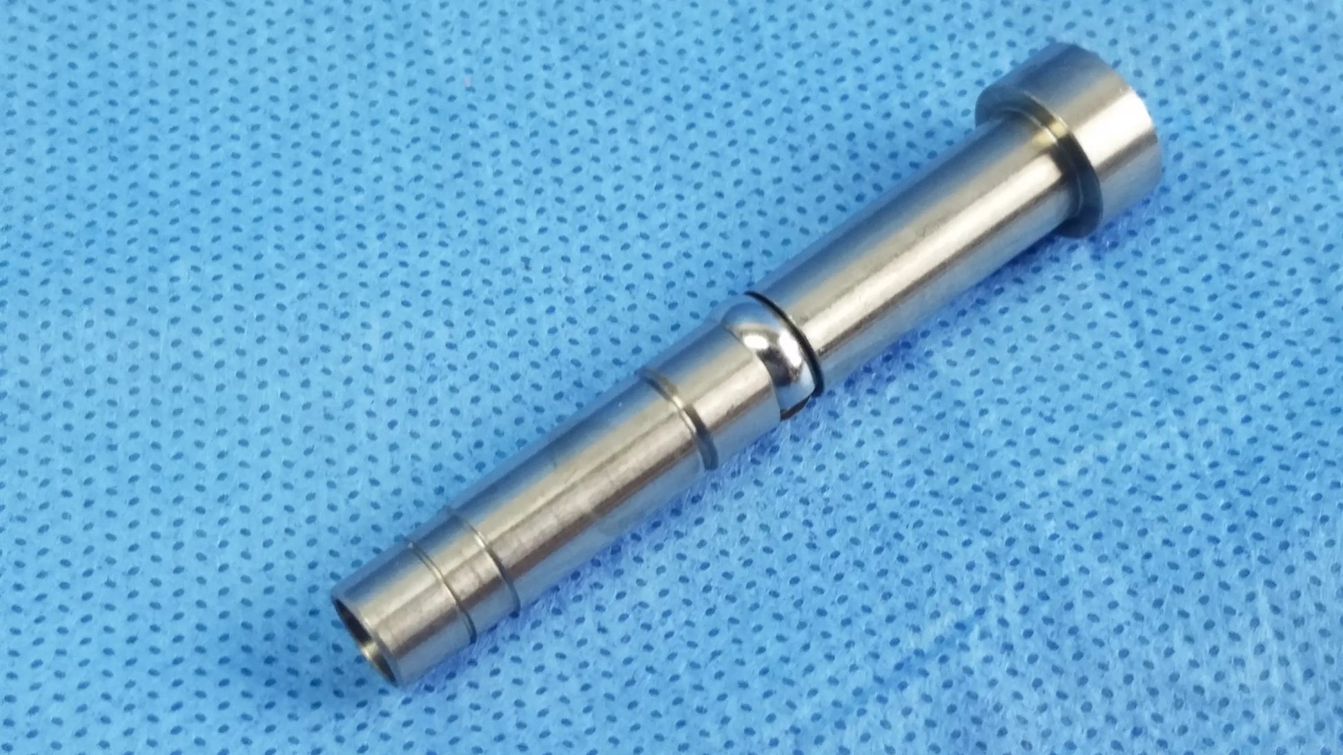 Silver metallic cylindrical rigid endoscope fiber interface adapter with machined grooves and threaded optical fiber connector