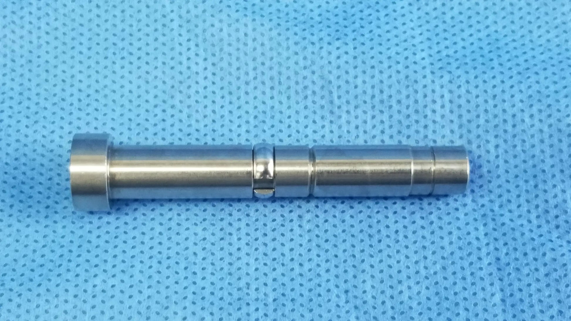 A sleek silver metal cylindrical rigid endoscope optical fiber interface adapter with polished segmented design