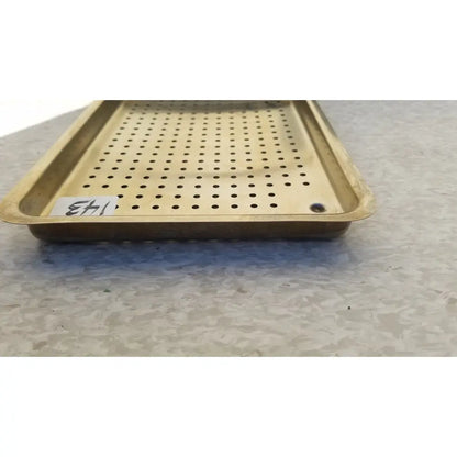 Gold-colored metal ritter autoclave sterilizer tray with evenly spaced perforations and raised edges for sterilization use