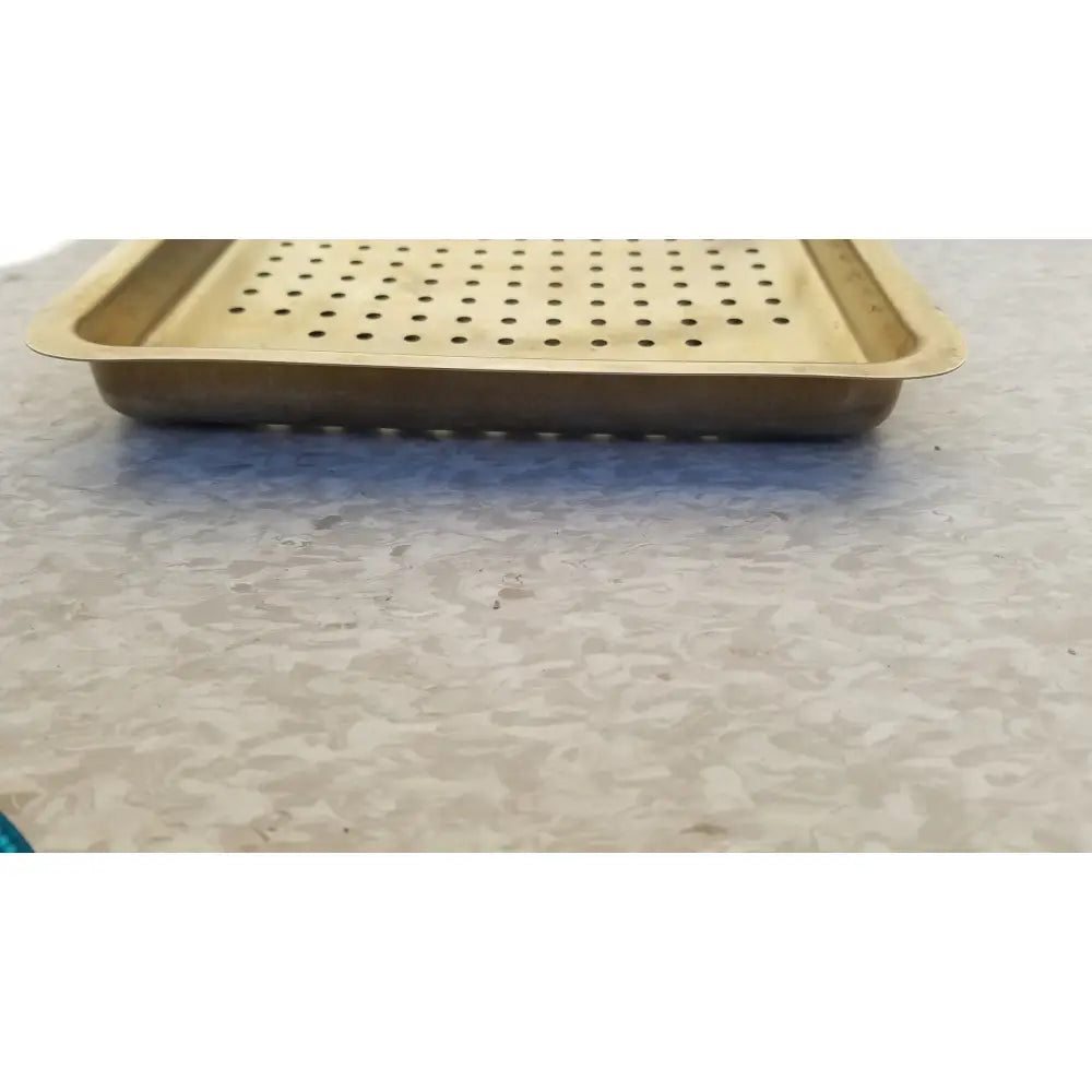 Gold-colored metal ritter autoclave sterilizer tray with perforated surface and raised edges for sterilization use