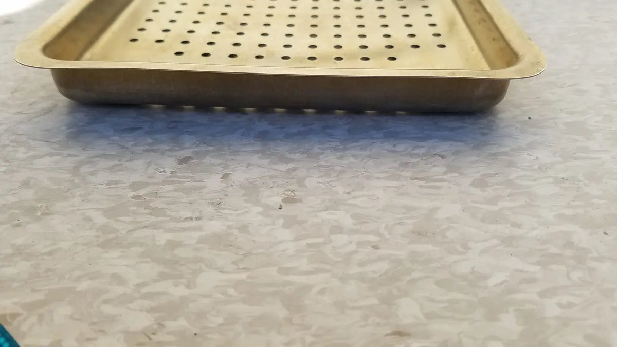 Gold-colored metal ritter autoclave sterilizer tray with perforated surface and raised edges for sterilization use