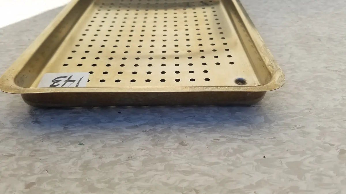 Gold-colored metal ritter autoclave sterilizer tray with evenly spaced perforations and raised edges for sterilization use