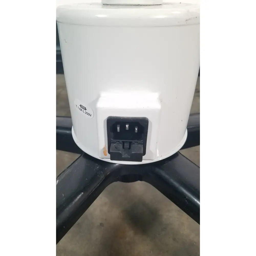 White cylindrical electric heater with black power plug and label on the back of ritter midmark 354-022 portable surgery procedure light