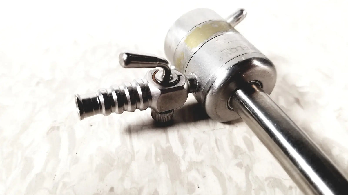 Silver rotating single stopcock cannula with threaded metallic shaft and engraved cylindrical handle for precise control