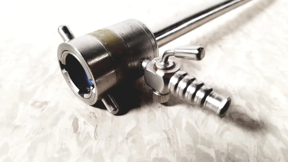 Stainless steel rotating single stopcock cannula with cylindrical body, threaded connectors, and adjustment knobs