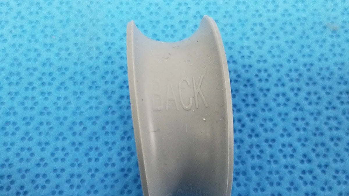 Gray plastic dental retainer showing back side with embossed back text in rubber ring front/back for reuse medical purposes