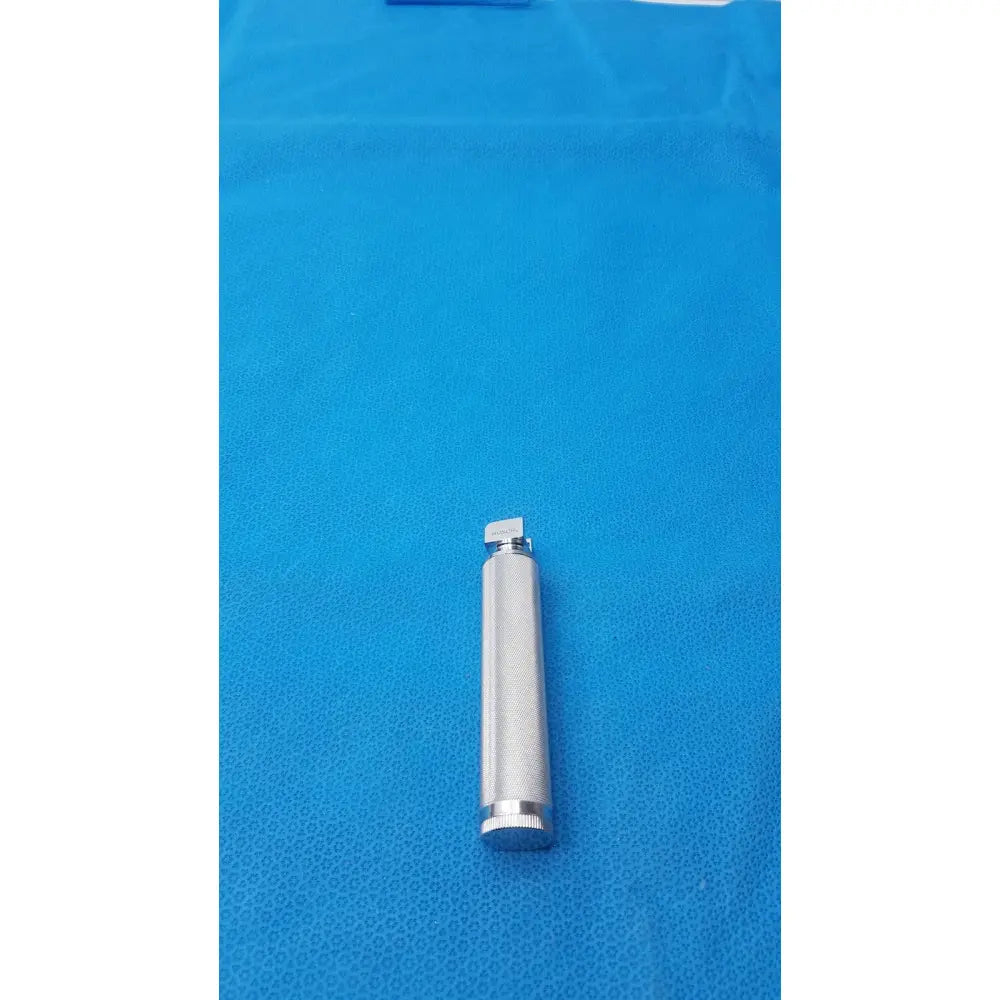 Silver metallic rusch standard laryngoscope short stubby handle with textured grip and small rectangular lens cap at top