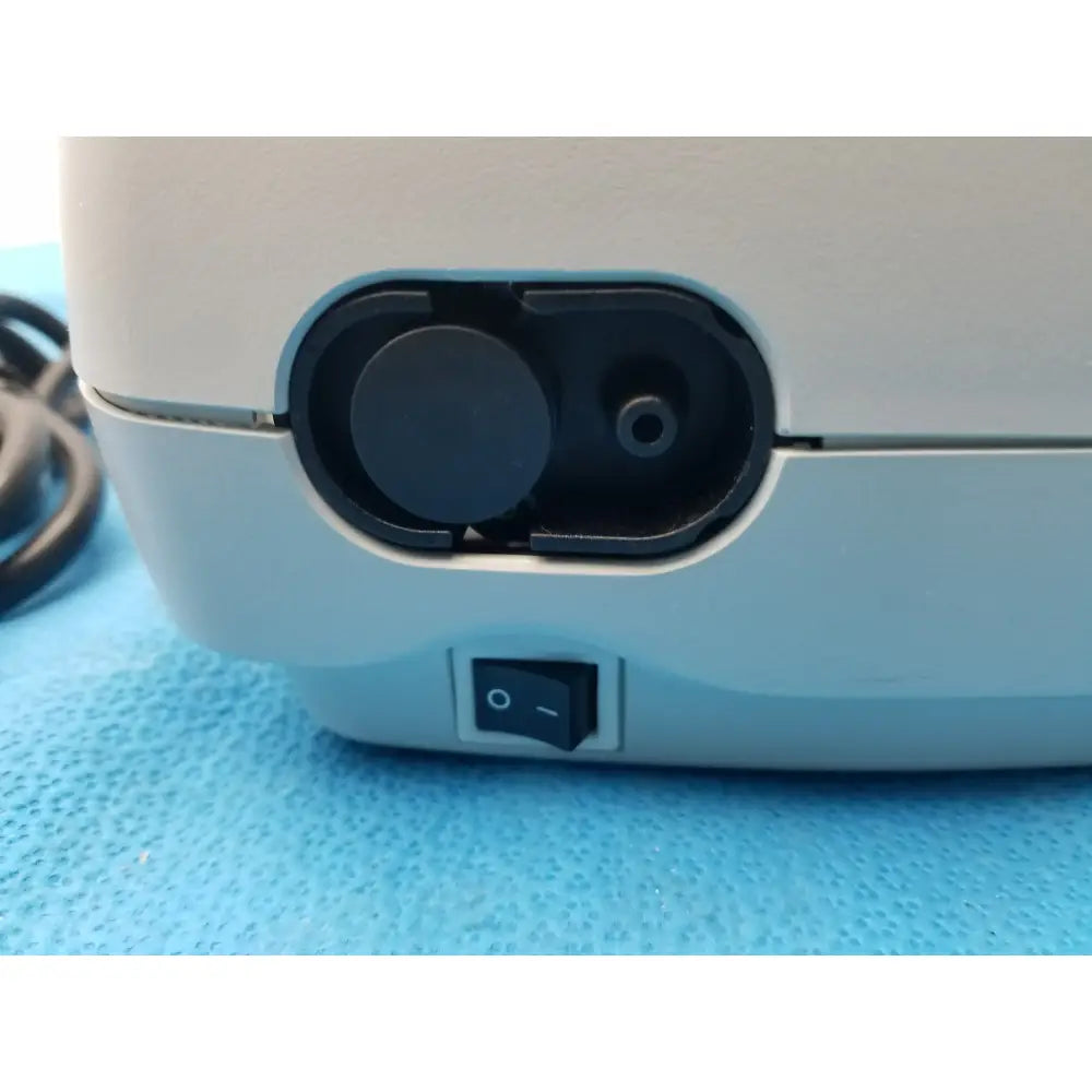 Light blue plastic salter labs aire elite compressor nebulizer with black circular port and power switch on the back side