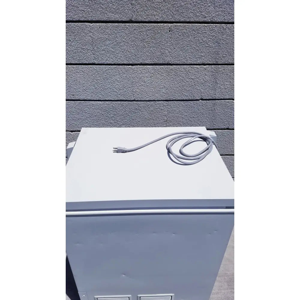 Gray coiled power cord resting atop a white sanyo vip series ultra low temperature freezer model mdf-c8v1 appliance