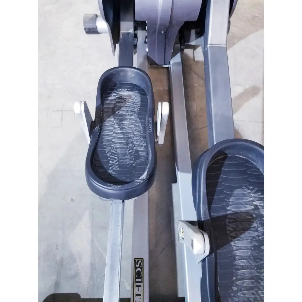 Black rubber footrests with textured wavy grip on gray metal frame of scifit sx7000 elliptical commercial lower body trainer