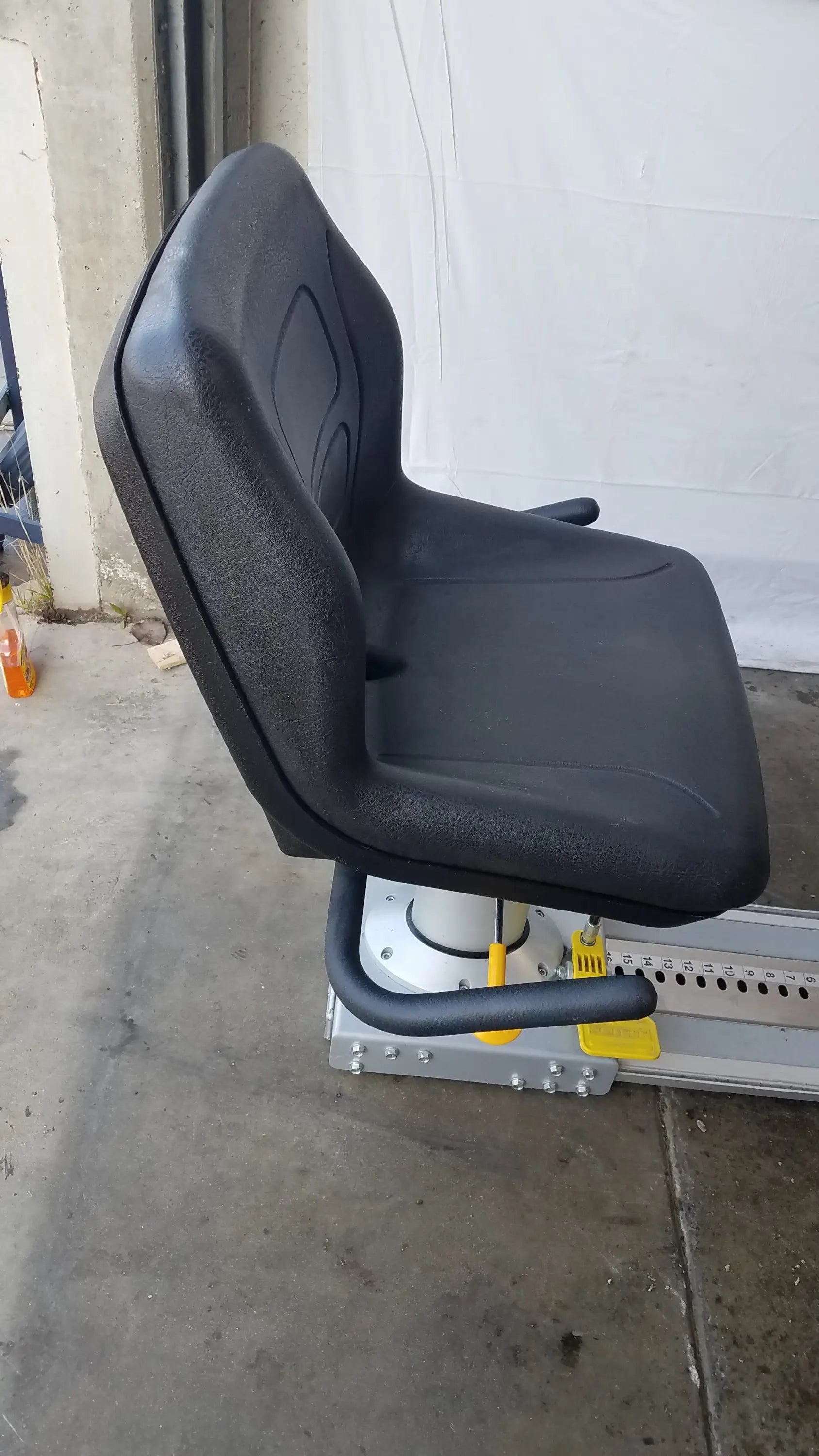 Black textured plastic operator seat with padded backrest on metal frame with yellow hydraulics on scifit systems rst7000 recumbent stepper
