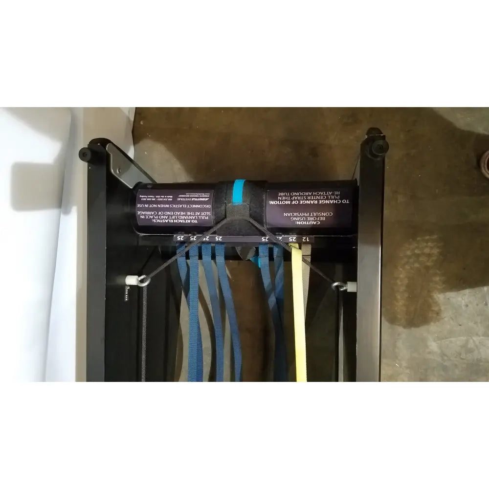 Black resistance band trainer with blue and yellow bands hanging from metal frame for shuttle recovery sport