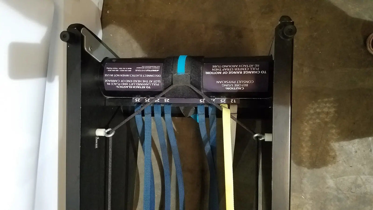 Black resistance band trainer with blue and yellow bands hanging from metal frame for shuttle recovery sport