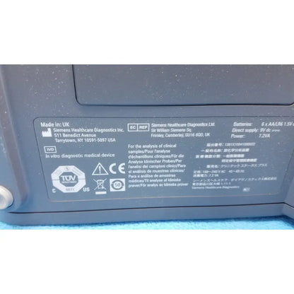 Gray plastic medical device label with black text and certification logos on siemens healthcare clinitek status analyzer
