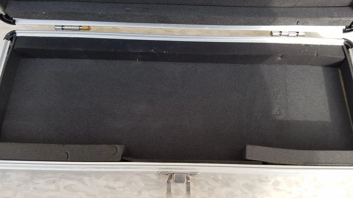 Silver hard protective aluminum keyboard case with black foam interior and molded compartments for secure storage
