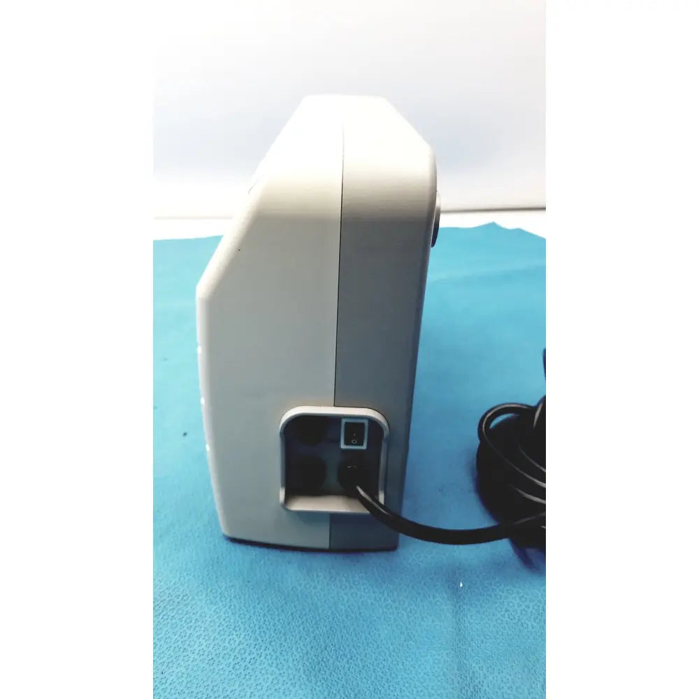 White and gray medical equipment air pump sizewise medical equipment with black power cord plugged into rear port