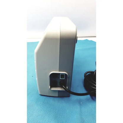 White and gray medical equipment air pump sizewise medical equipment with black power cord plugged into rear port