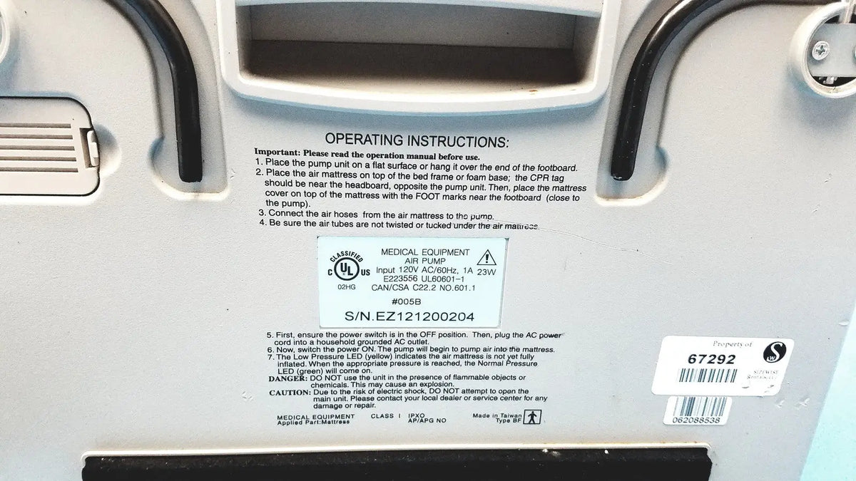 White plastic sizewise medical equipment air pump with black rubber hoses and label showing model and serial numbers
