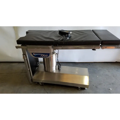Skytron 1700 surgical table with hand control featuring a black padded surface and stainless steel frame for reuse medical use
