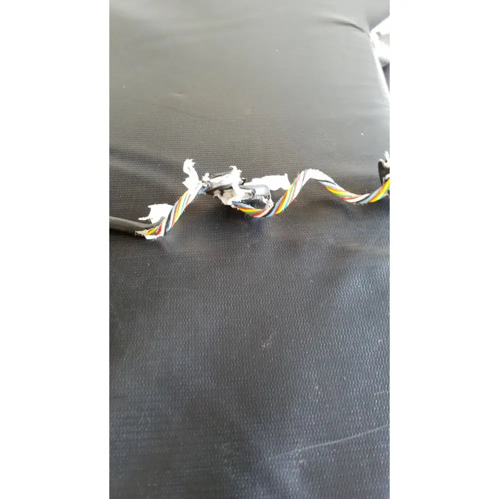 A frayed multi-colored twisted cable with exposed wires from the back side of skytron 1700 surgical table hand control medical equipment