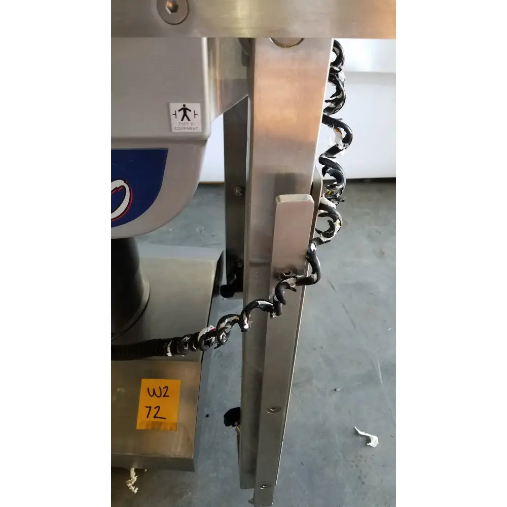 Black coiled cable attached to metallic component of skytron 1700 surgical table hand control medical equipment back side
