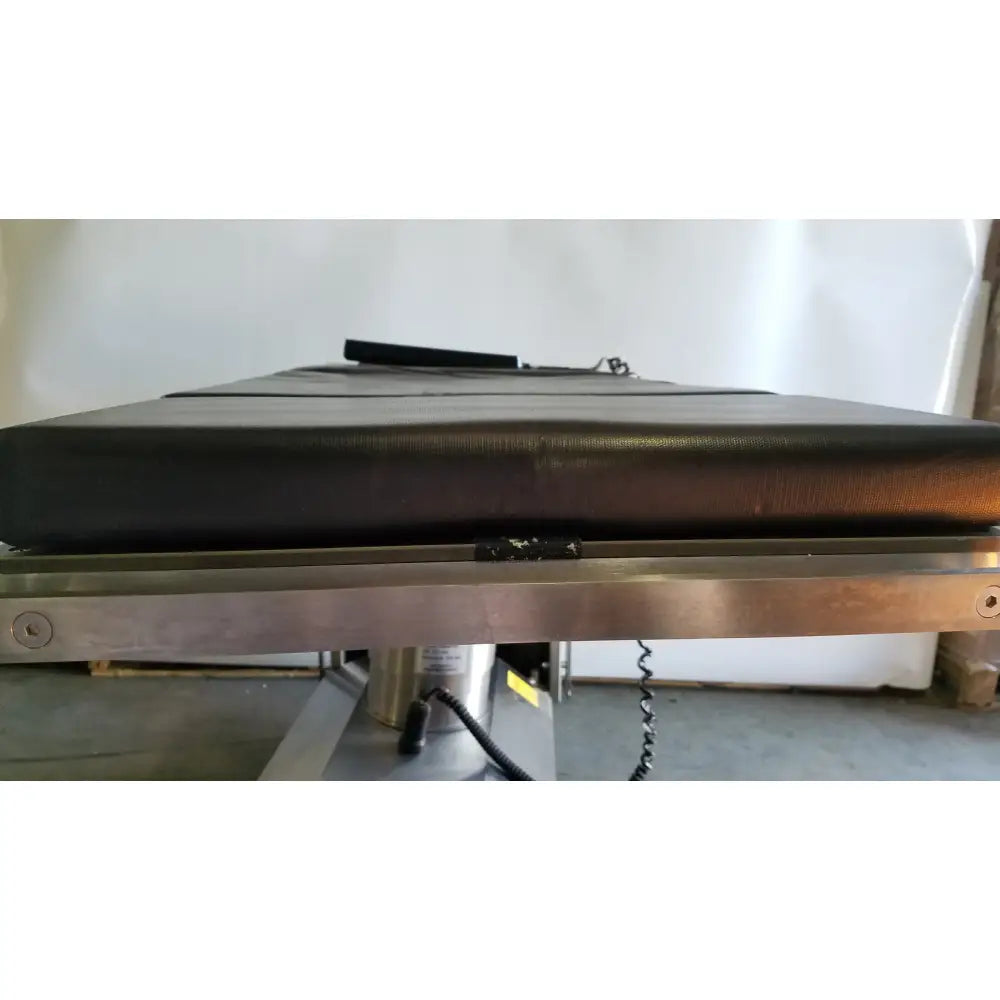 Black leather Skytron 1700 surgical table with metallic frame featuring hand control for precise medical equipment use