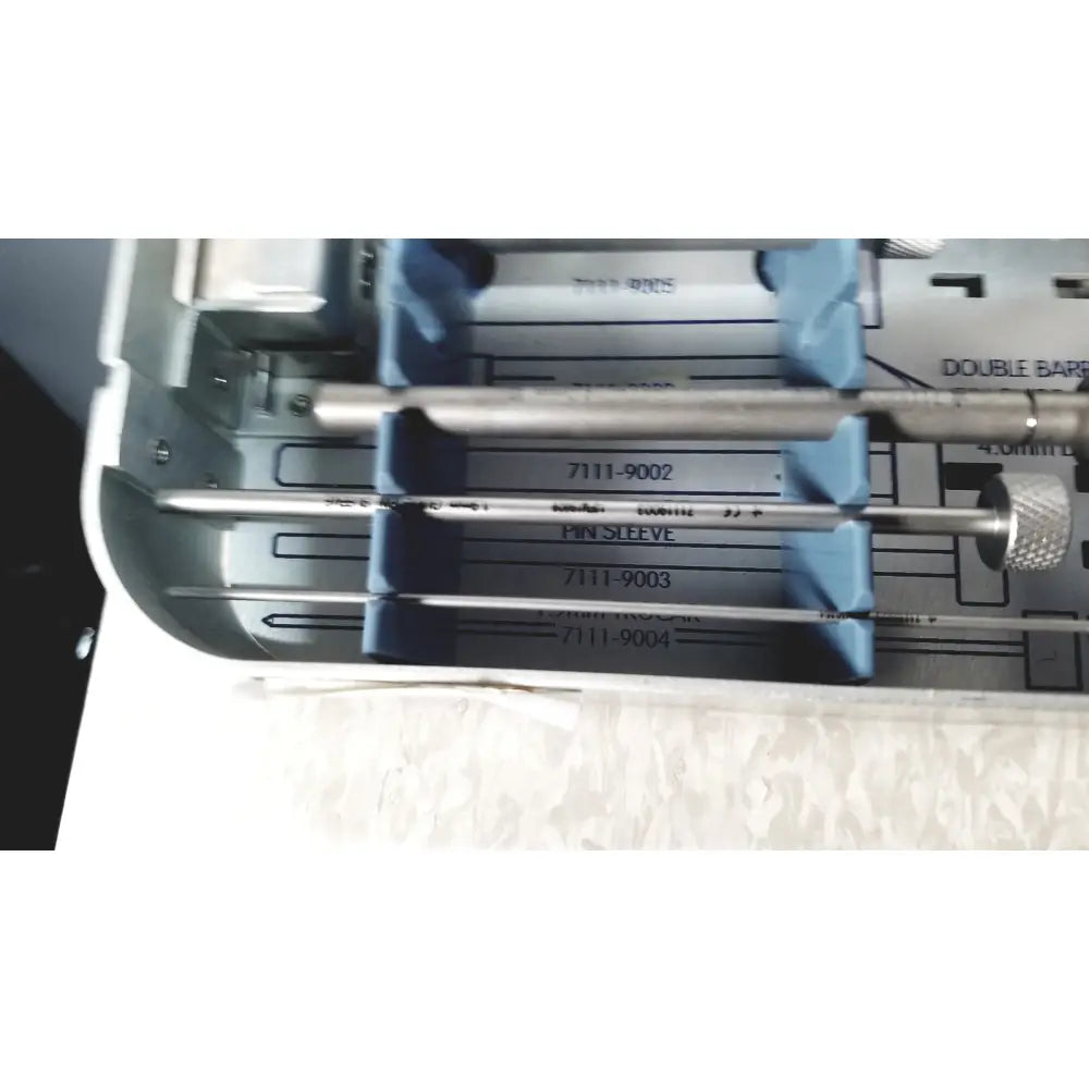 Silver-colored metal pin sleeves with knurled knobs in gray tray of smith & nephew 5.5 mm cannulated screw set instrument tray